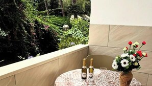 A small round table with a patterned tablecloth, two bottles, and a vase of flowers on a balcony. - Marianna 's House newly renovated apartment in Naples near airport (Napoli)