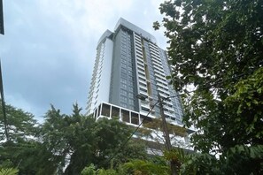Een hoog, modern gebouw met een witte gevel en meerdere balkons.