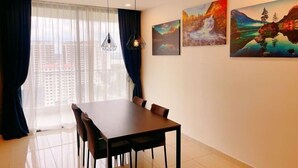 A dining area with a table and chairs, a window with curtains, and two paintings on the wall. - GYDEN STAYCATION #The Straits Johor Bahru (Johor Bahru)