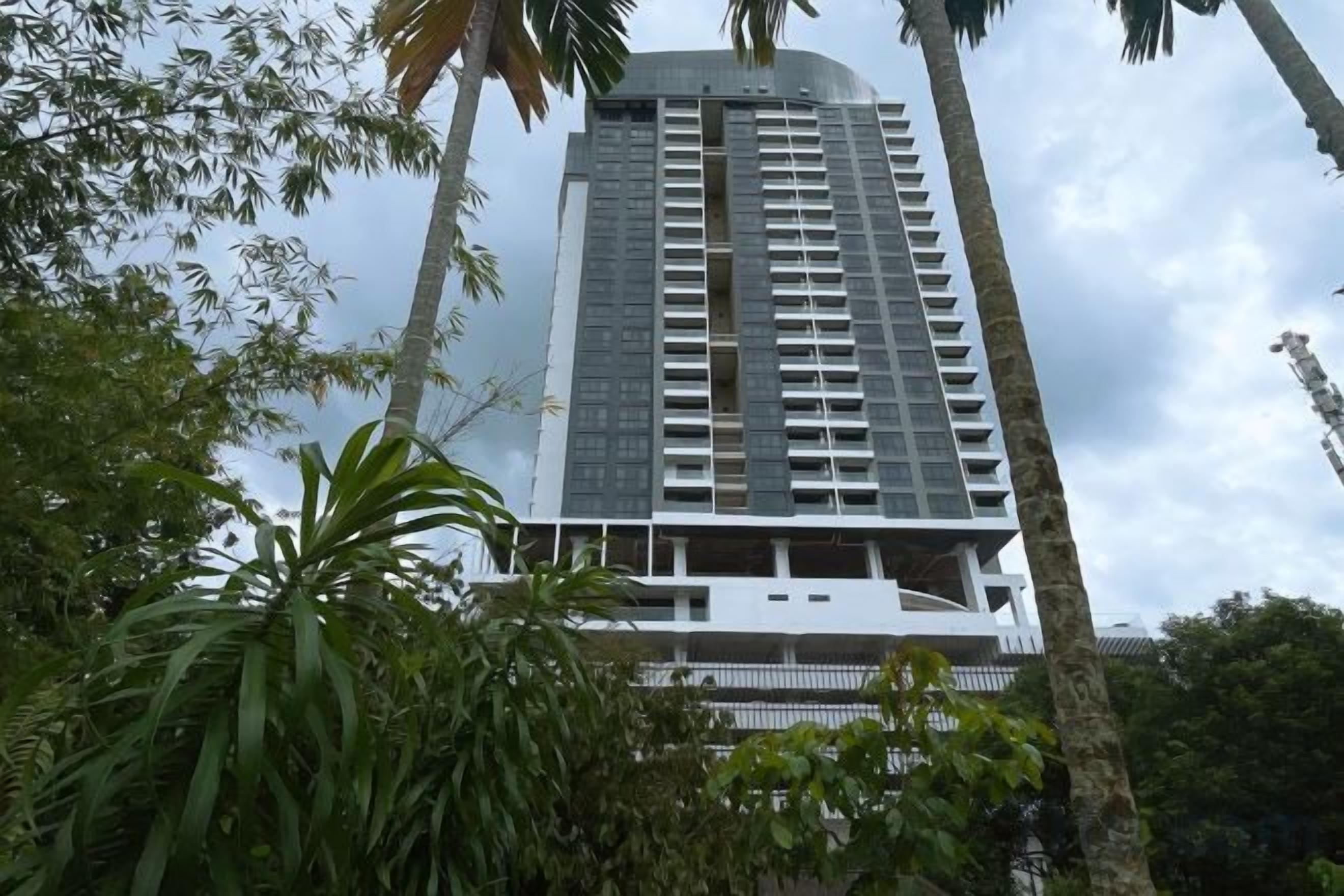 A tall building with multiple floors, surrounded by greenery.