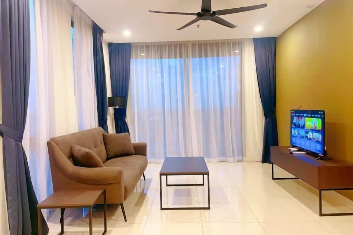 Un salon moderne avec un canapé, une table basse, un téléviseur posé sur un meuble et un ventilateur de plafond.