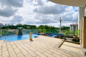 En pool på taget med frit udsyn til byens skyline, omgivet af glasgelænder og plantekasser.