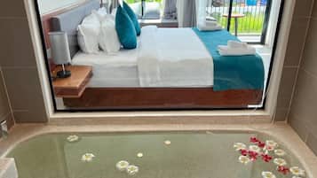 Et hotelværelse med en seng, et badekar med blomster og udsigt til en pool og en bygning.