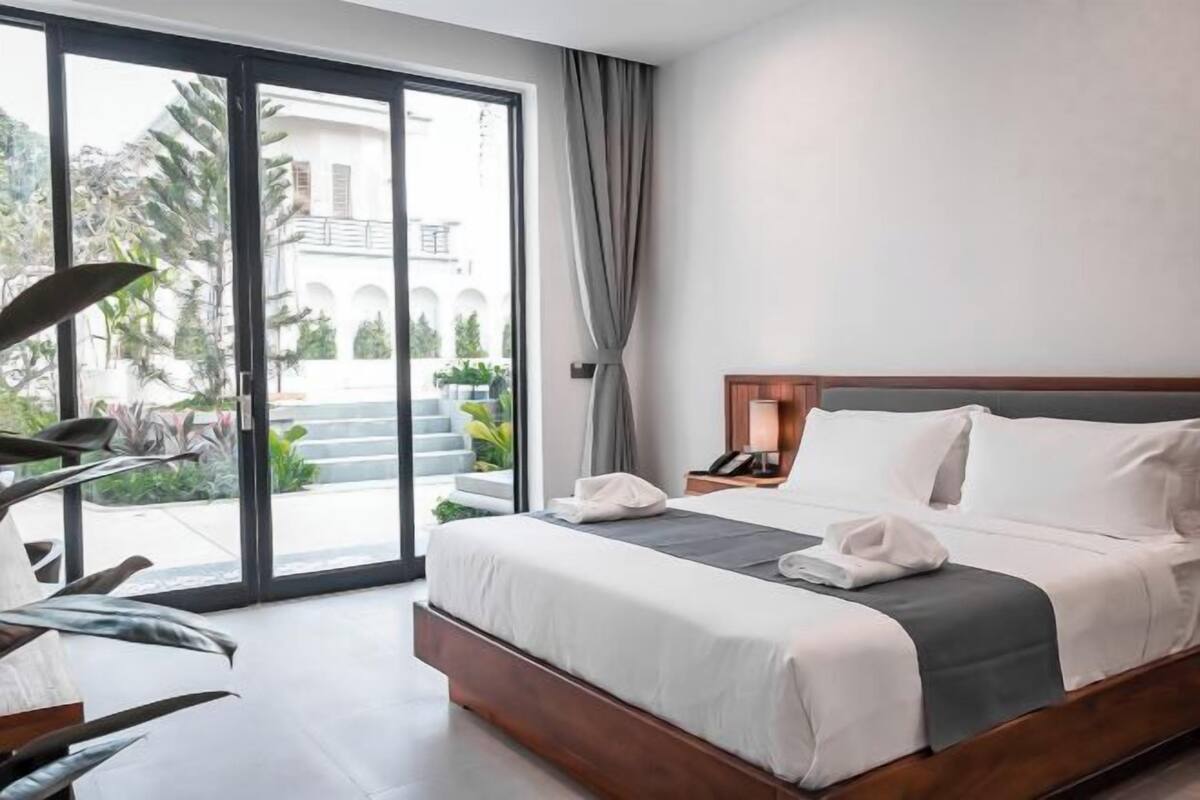 Une chambre d’hôtel avec un lit, un bureau, une lampe et une vue sur l’extérieur.