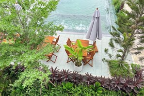 A patio with a table and chairs, surrounded by lush greenery and overlooking a body of water. - Emerald Residence - Kampot (Kampot)