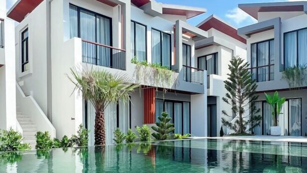 A modern hotel with a pool, multiple balconies, and a staircase leading to the upper floors.