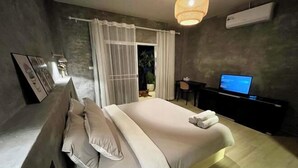 A modern bedroom with a large bed, a desk with a computer, and a view of the outdoors. - The Summer Cottage (Koh Chang)