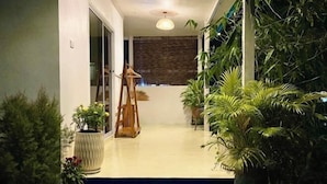 A hallway with a wooden easel, potted plants, and a textured wall. - The Summer Cottage (Koh Chang)