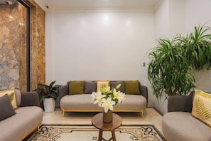 A modern living room with a sofa set, a coffee table with flowers, and a large potted plant. - Nature Hotel - Le Dai Hanh (Dalat)