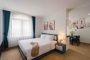 A hotel room with a bed, bedside table, lamp, and a desk with chairs. - Nature Hotel - Le Dai Hanh (Dalat)