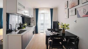 A modern kitchen with a dining area, featuring a long countertop, cabinets, and a dining table with chairs. - Nature Hotel - Le Dai Hanh (Dalat)
