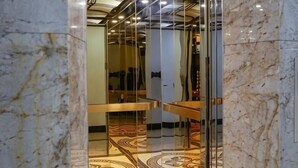 A marble lobby with a glass elevator, patterned carpet, and a modern ceiling design. - Nature Hotel - Le Dai Hanh (Dalat)
