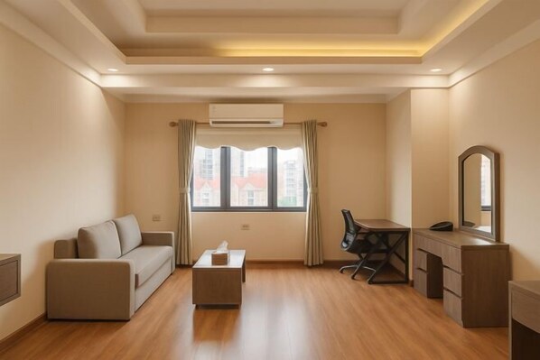 Een moderne kamer met een bank, een bureau, een stoel, een klein tafeltje en een spiegel.