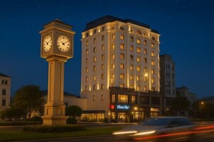 Un hotel con una torre de reloj, un edificio grande de varios pisos y un cartel que dice "Place Hur".