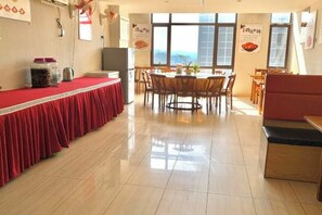 A dining area with a red tablecloth-covered table, chairs, and a booth.