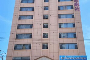 Un edificio de varios pisos con fachada uniforme, numerosas ventanas y una entrada visible.