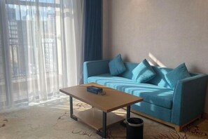 A room with a blue sofa, a wooden coffee table, and a trash bin.