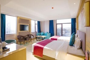 Habitación de hotel con dos camas, un escritorio, una silla, una mesita y un televisor.