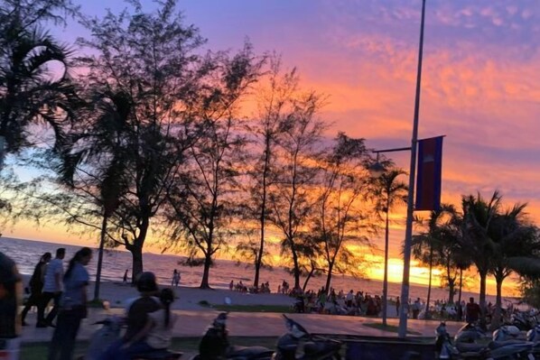 Vista de un atardecer con árboles y una playa.