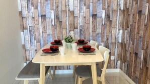 A dining table with four chairs, a white tablecloth, and a decorative wall with wooden panels. - Comfy Private Home @ Sky.Pod (Puchong)