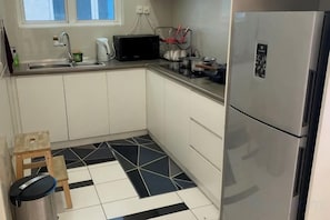A compact kitchen with a refrigerator, microwave, and sink. - Comfy Private Home @ Sky.Pod (Puchong)