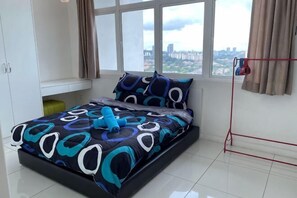 Een slaapkamer met een bed, een raam met uitzicht op de stad, een rode metalen standaard en een witte kledingkast.