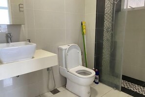 Une salle de bain avec un lavabo blanc, des toilettes et un espace douche.
