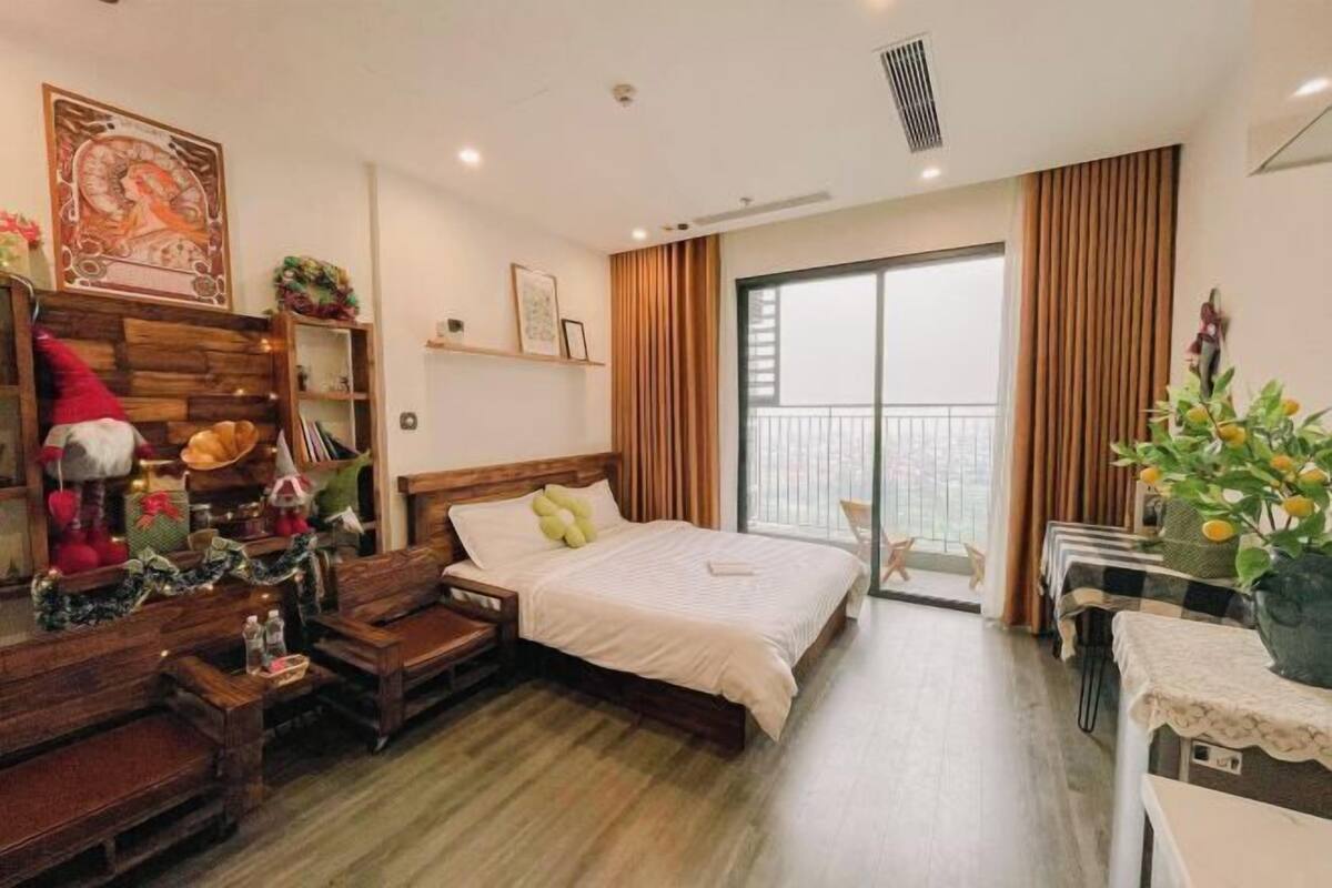 A hotel room with a wooden bed, a desk, a chair, a balcony with a view, and a large window.