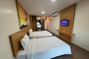 A hotel room with two beds, a TV, an air conditioner, and a painting on the wall. - Delta Chenang Resort (Langkawi)