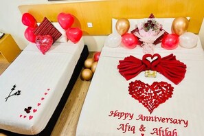 Two beds with decorative arrangements, including heart-shaped items and balloons, and a message on the bed on the right. - Delta Chenang Resort (Langkawi)