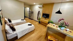 Habitación de hotel con dos camas, un escritorio, un televisor y una pequeña zona de estar.