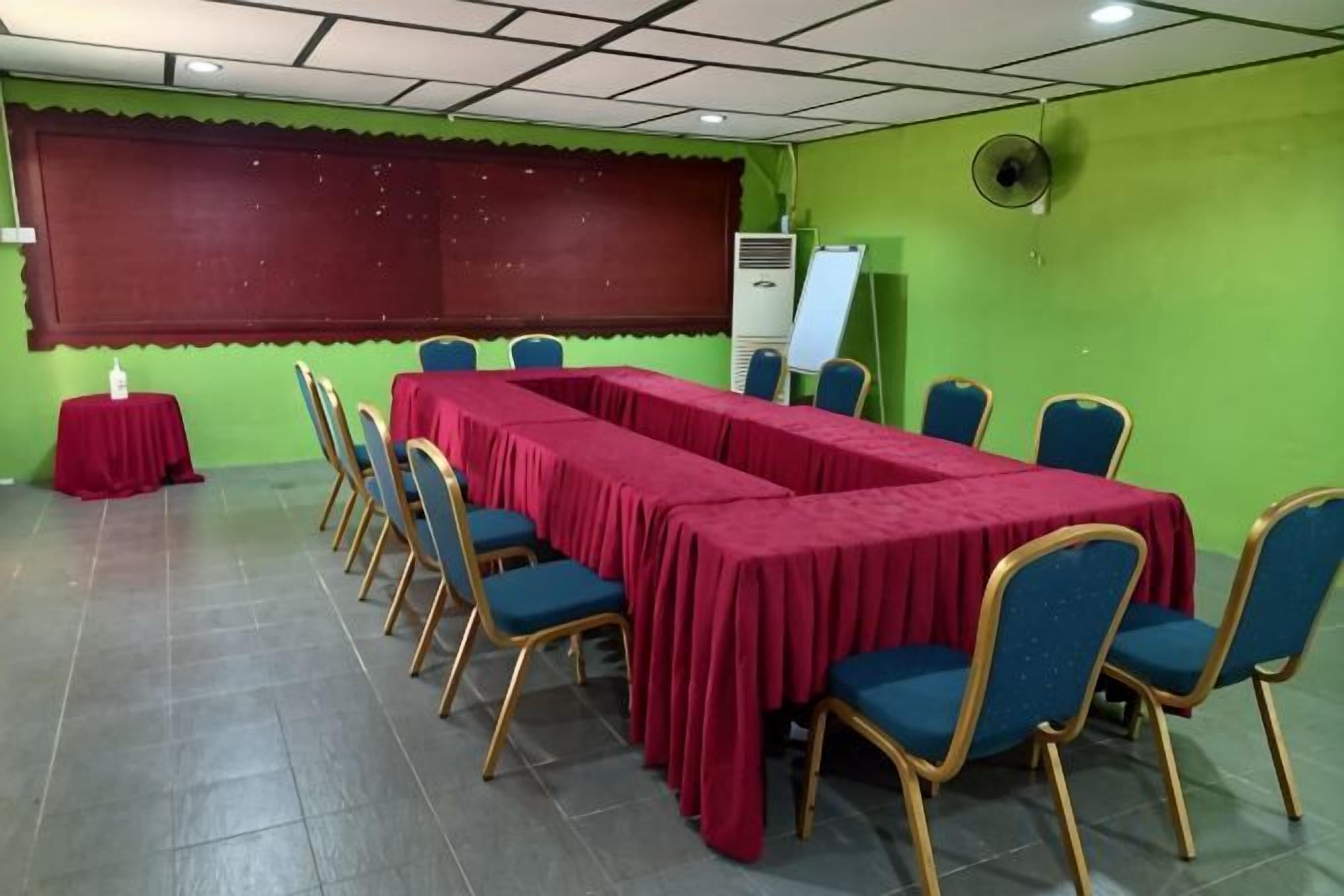 A conference room with a long table, chairs, a projector screen, and a whiteboard.