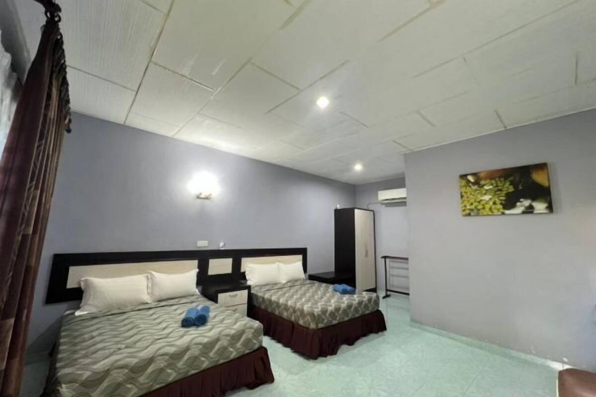 A hotel room with two beds, a wardrobe, a mirror, and a painting on the wall.