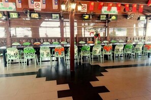 Un restaurante con varias mesas y sillas, piso de baldosas y pared de ladrillo.
