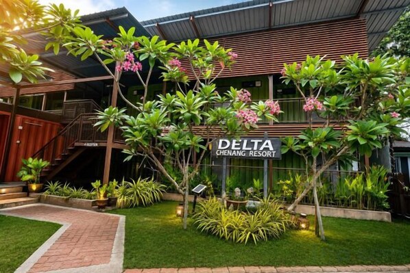 Resort genaamd DELTA CHENANG RESORT met een bordje, omringd door verzorgde beplanting en een geplaveid pad.