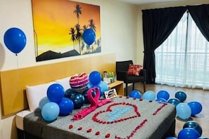 A hotel room with a bed, a painting, a window with curtains, and balloons. - Delta Chenang Resort (Langkawi)