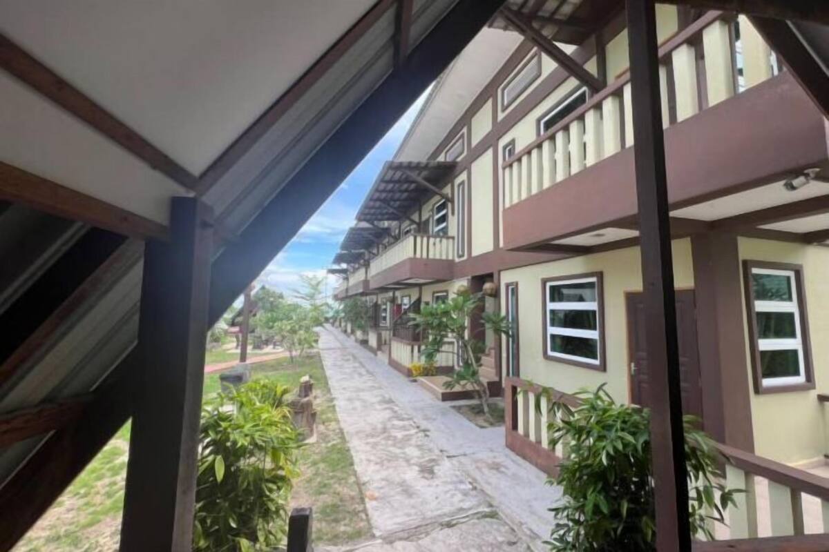 A building with multiple balconies and windows, a covered walkway, and a pathway leading to the building.