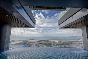 A modern hotel room with a large glass window, a view of the cityscape, and a ceiling with a geometric design. - Seascape Palace Hotel (Sihanoukville)
