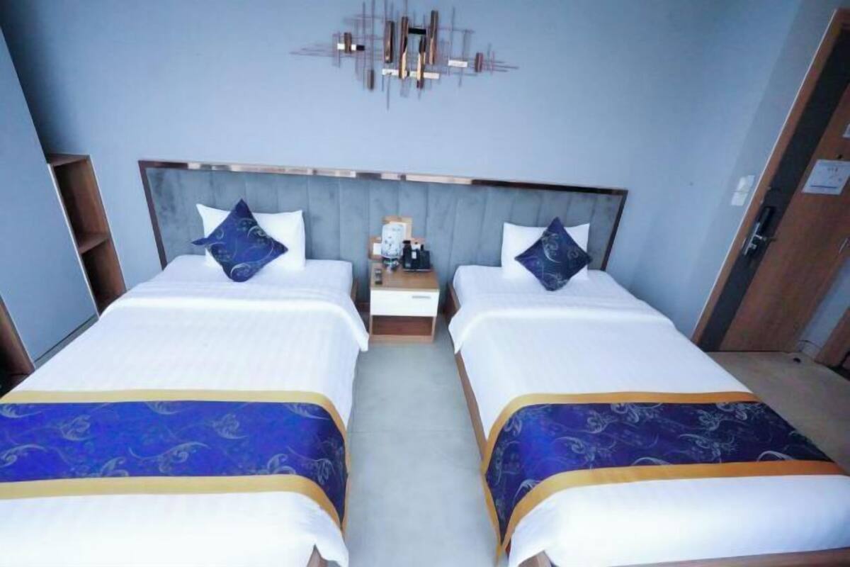 A hotel room with two beds, a nightstand, and a modern wall art piece.