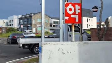 Rua com carros estacionados e edifícios ao fundo.