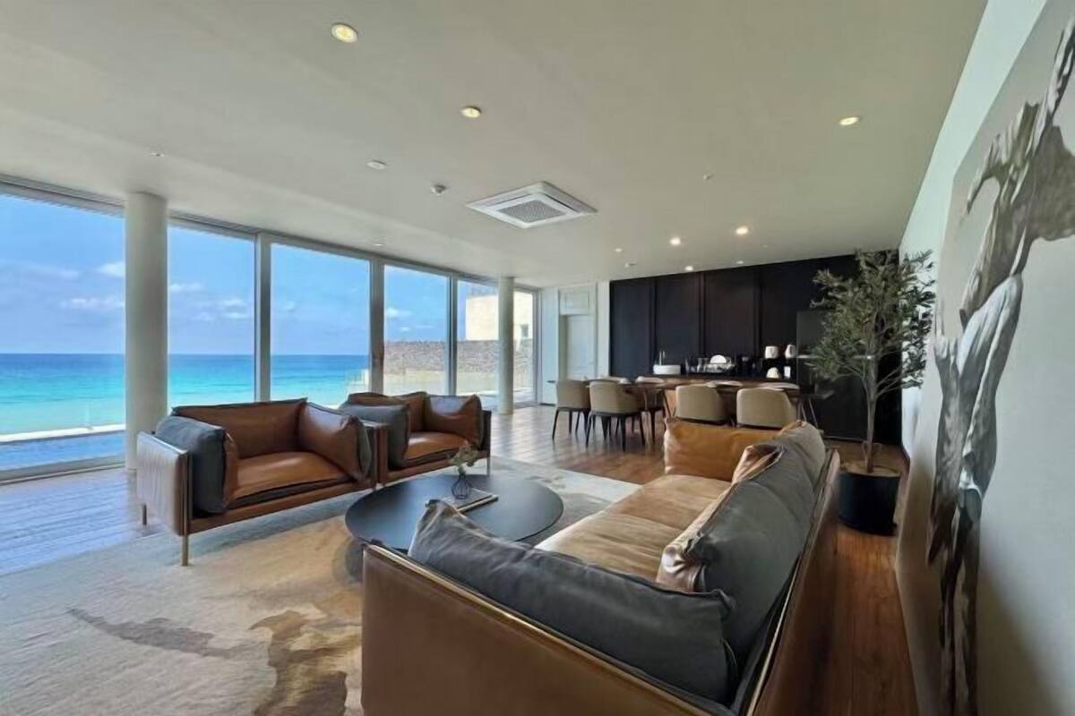 A spacious living area with a view of the ocean, a dining area, and a kitchen.