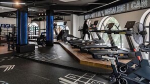 Un gimnasio moderno con cintas de correr, máquinas de pesas y una frase motivacional en la pared.