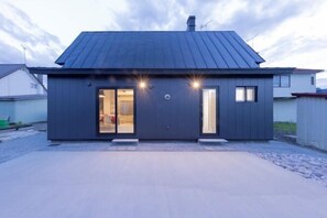 A modern two-story house with a dark exterior, large glass doors, and a metal roof. - Biei Villa Gen (Kamikawa District)