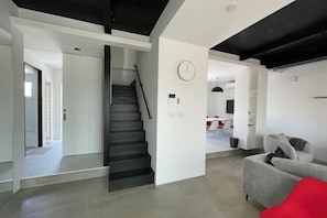 En modern inredning med en trappa, ett vardagsrum med en soffa och en matplats.