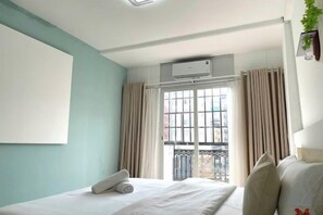A hotel room with a bed, a window with curtains, an air conditioning unit, and a view of the outside. - Ann Home (Ho Chi Minh City)