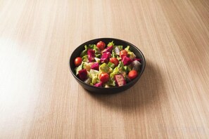 A bowl of salad on a wooden surface. - Itel Backpacker (Vientiane)
