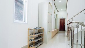 Un pasillo limpio y bien iluminado con un zapatero, un banco de madera y una escalera con barandilla de metal.