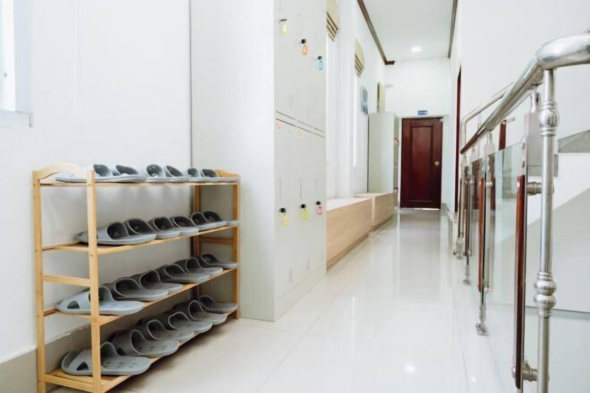 A clean, modern hallway with a shoe rack, a wooden bench, and a staircase with a glass railing.