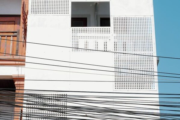 Fachada de edificio con pared blanca y balcón de madera.