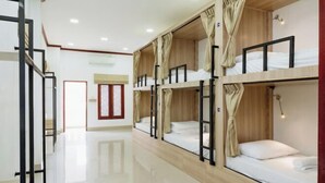 Habitación de hotel con literas, suelo de madera, una puerta y una ventana.